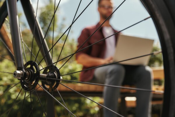 Image of worker on a laptop taken through a bicycle wheel as illustration for post 'Flexible working will become the ‘new normal’.  