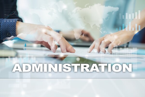 Image of two business owners at a meeting table with the word 'Administration' overlaid as illustration for post 'What does administration mean to a Company?'