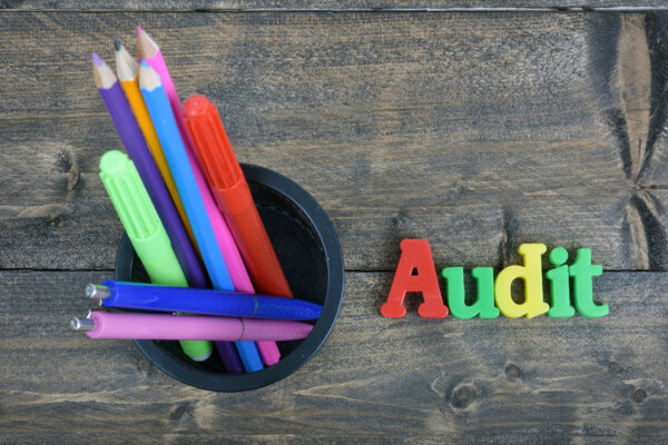 Image of a pen pot on a wooden desk with the word 'audit' spelled out in colourful plastic letters, as illustration for post 'Internal Audit – Where do you start?'