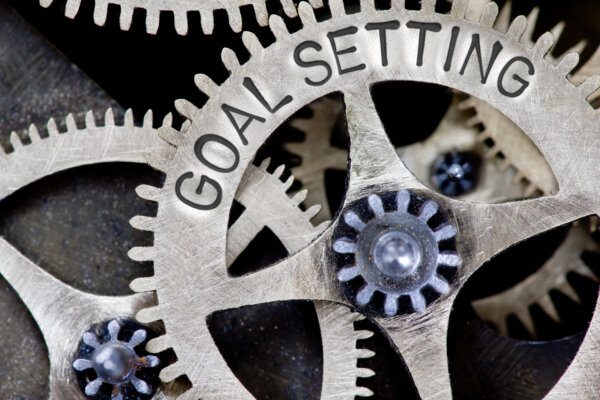 A close up image of cogs, engraved with the words 'Goal Setting' as illustration for post 'Setting Financial Goals for Success'.