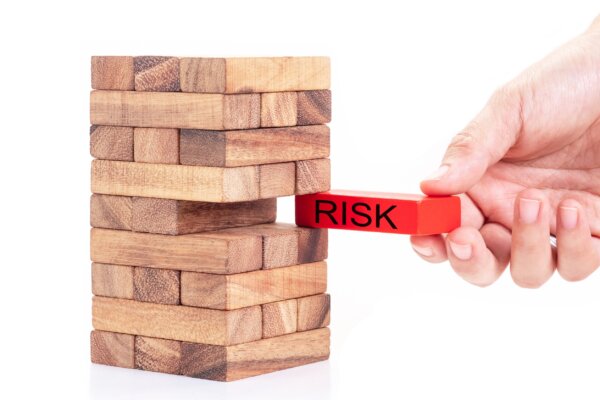 Image of Jenga-style pile of wooden blocks with a red-painted one with the word 'risk' written on it being removed slowly as illustration for post 'Managing key person risk'.