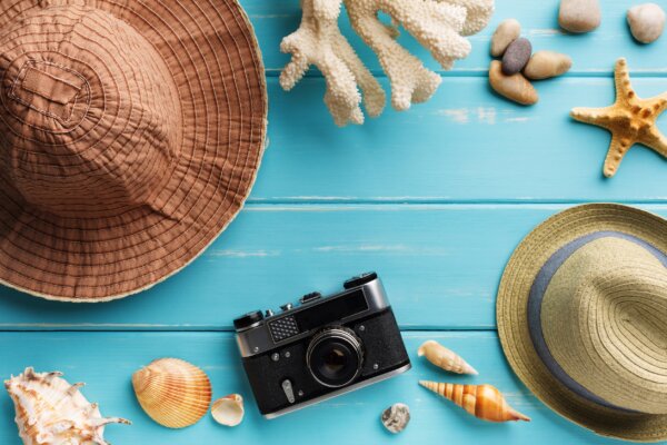 Image of a sunhat, camera, shells and other summer and beach items as illustration for post 'Holiday pay and entitlement reforms.'