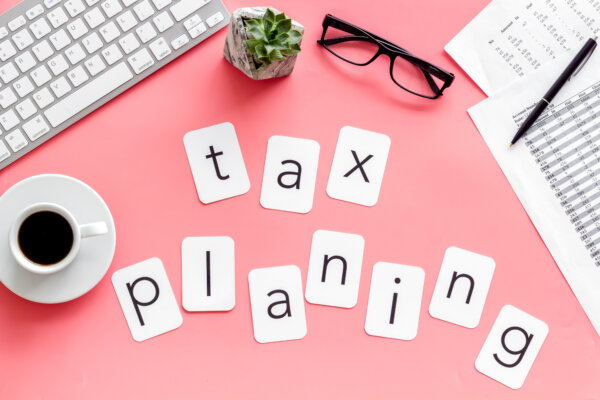 An image of the words 'tax planning' made out of white letter cards on a pink desk top, with office equipments around, as illustration for post 'Can you save on Capital Gains Tax?'
