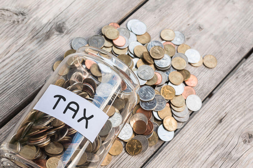 An image of a money jar labeled 'tax' with coins on wood table as illustration for post 'Corporation Tax updated...'