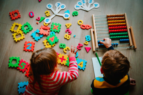 Image of two young children playing with brightly coloured blocks and an abacas as illustration for post 'Are you or your employees making good use of Tax-Free Childcare?'