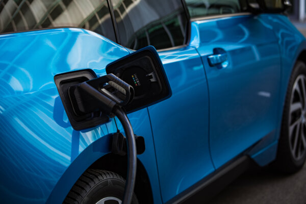 Image of a blue electric vehicle being charged as illustration for post 'Charging electric cars at home.'