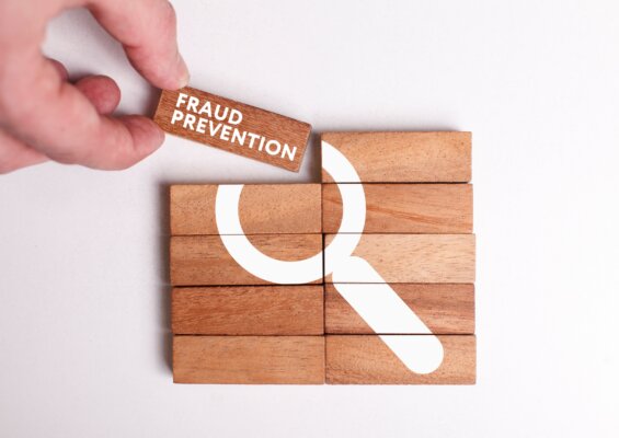 Image of wooden blocks with a magnifying glass painted across them, with one being moved into place saying 'fraud prevention' as illustration for post 'The Economic Crime and Corporate Transparency Act – what it means to you!'