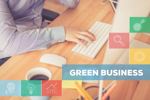 An image of a business owner at a mac, using an apple keyboard and mouse at a desk overlaid with images of green related icons and the words 'green business' as illustration for post 'UK Business Climate Hub helps businesses save money and go green.'