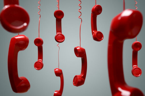 Image of multiple red phone handsets hanging by their cords as illustration for post 'HMRC call wait times'.