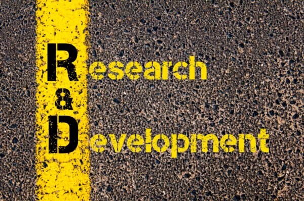 'Research and Development' written in yellow paint on a tarmac road surface, as illustration for post 'Research & Development (R&D) Reliefs'