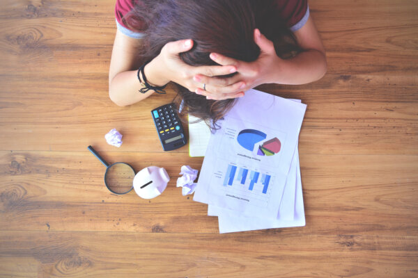 An aerial image of a stressed business owner trying to work out their finances, looking at graphs and their calculator, as illustration for post 'Employers National Insurance Changes: What You Need to Know'